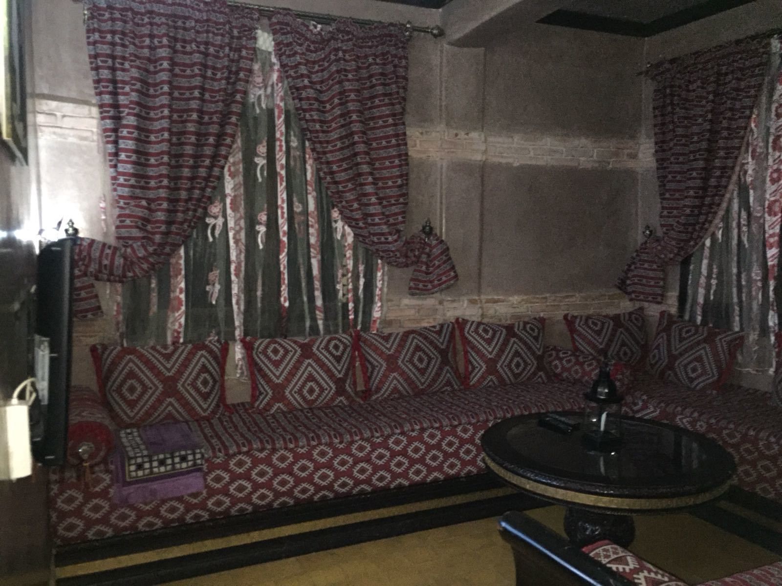 Um quarto com um sofá estampado, uma mesa redonda e cortinas com padrão geométrico.
