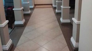 Un pasillo con suelo de baldosas y columnas blancas.