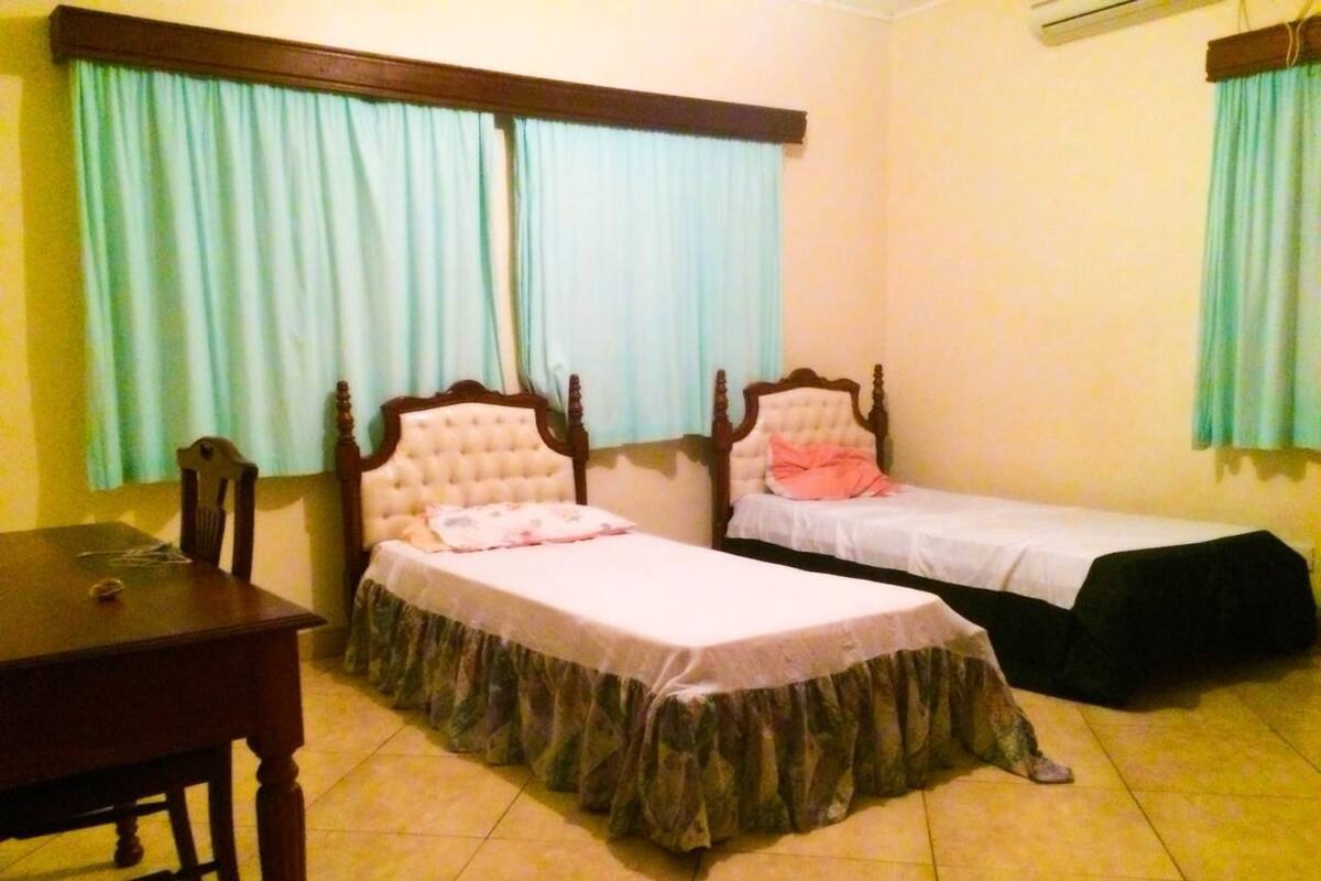 A room with two single beds, a wooden table, and a chair.