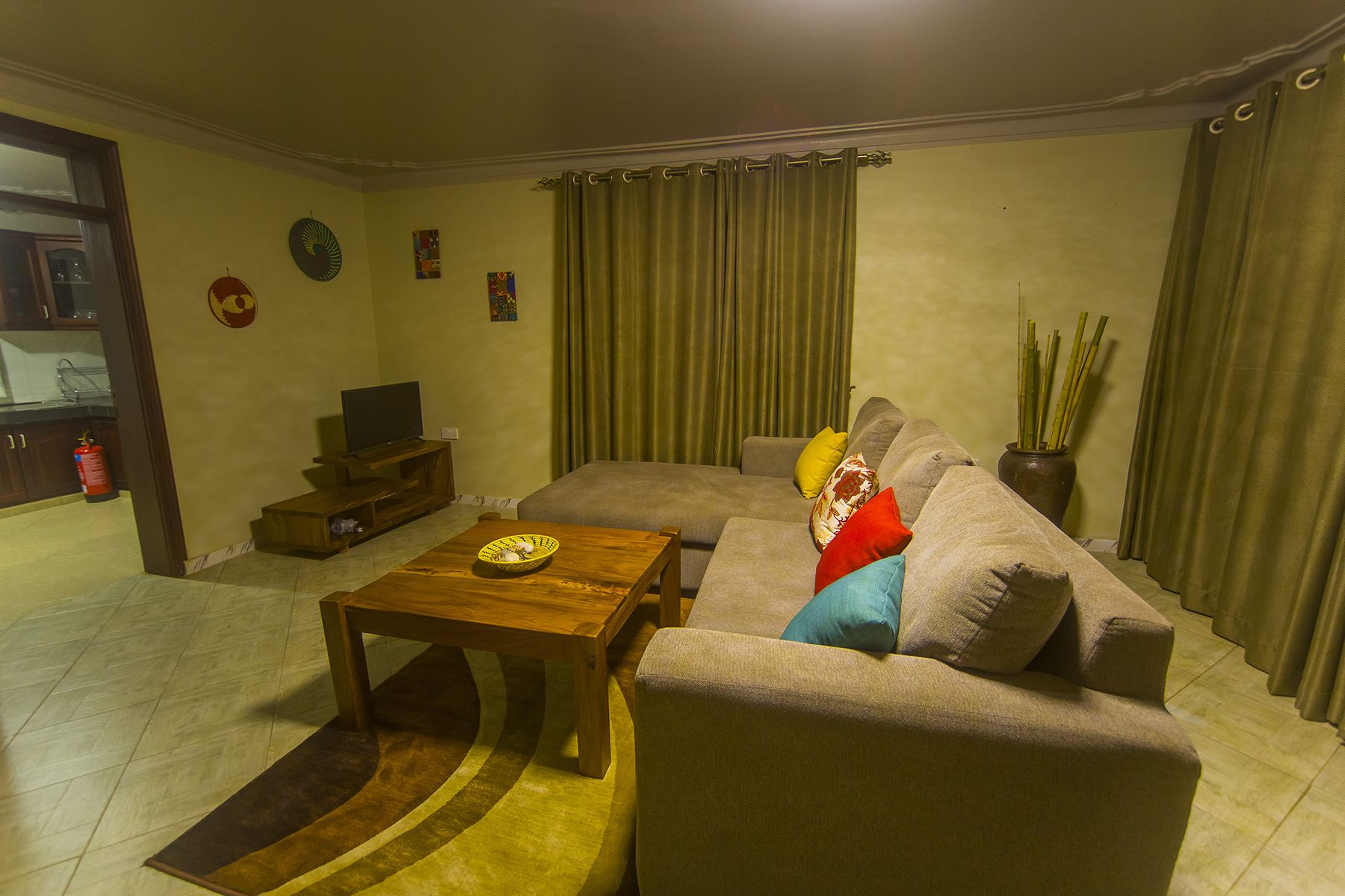 A living room with a sofa, a coffee table, a television on a stand, and a vase with plants.