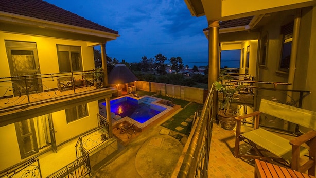 A two-story building with a balcony overlooking a swimming pool and a view of the sea. - Victoria Breeze Hotel Apartment (Iganga)