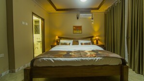 A hotel room with a wooden bed, two bedside lamps, a ceiling light, and a window with curtains. - Victoria Breeze Hotel Apartment (Iganga)