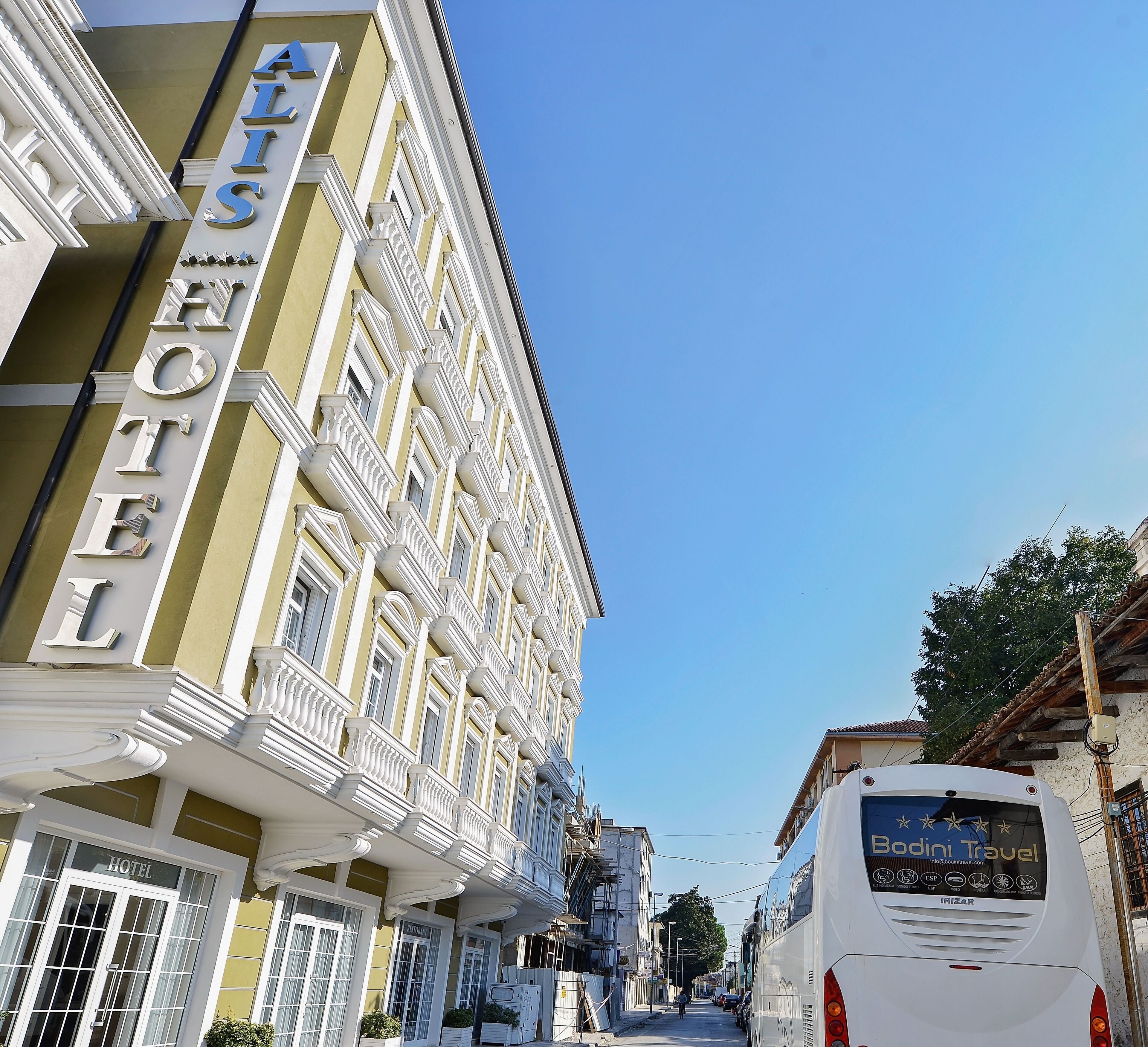 A hotel with a prominent sign, a street view, and a bus in the background.