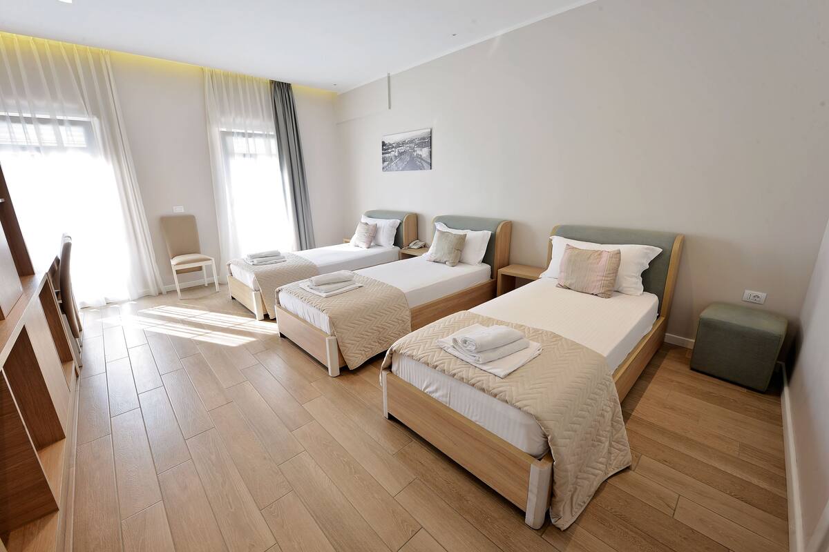 A hotel room with two beds, a desk, and a chair.
