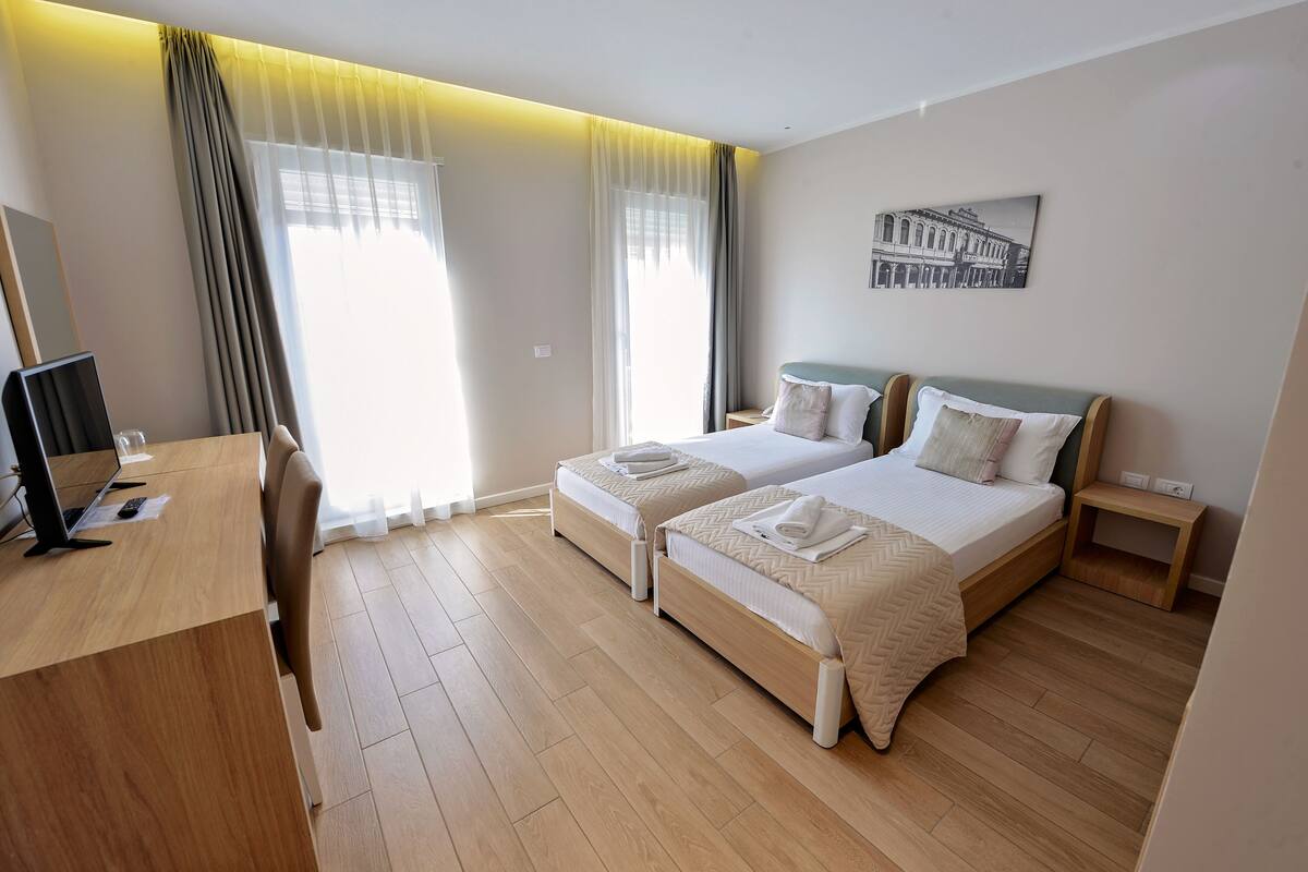 A hotel room with two beds, a desk, and a chair.