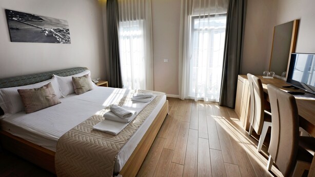 Et hotelværelse med seng, skrivebord og fjernsyn.