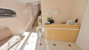 Et hotellets receptionsområde med en receptionsdisk, en sofa og en trappe.