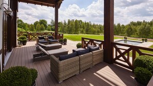 A covered outdoor deck with wicker furniture, a pool table, and a view of a golf course. - Siedlisko 518 Wzgorza Dylewskie (Ostróda)
