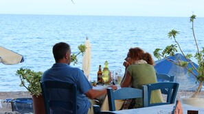 A seaside restaurant with a table set for two, overlooking the ocean. - Alkioni Sea View (Sitia)