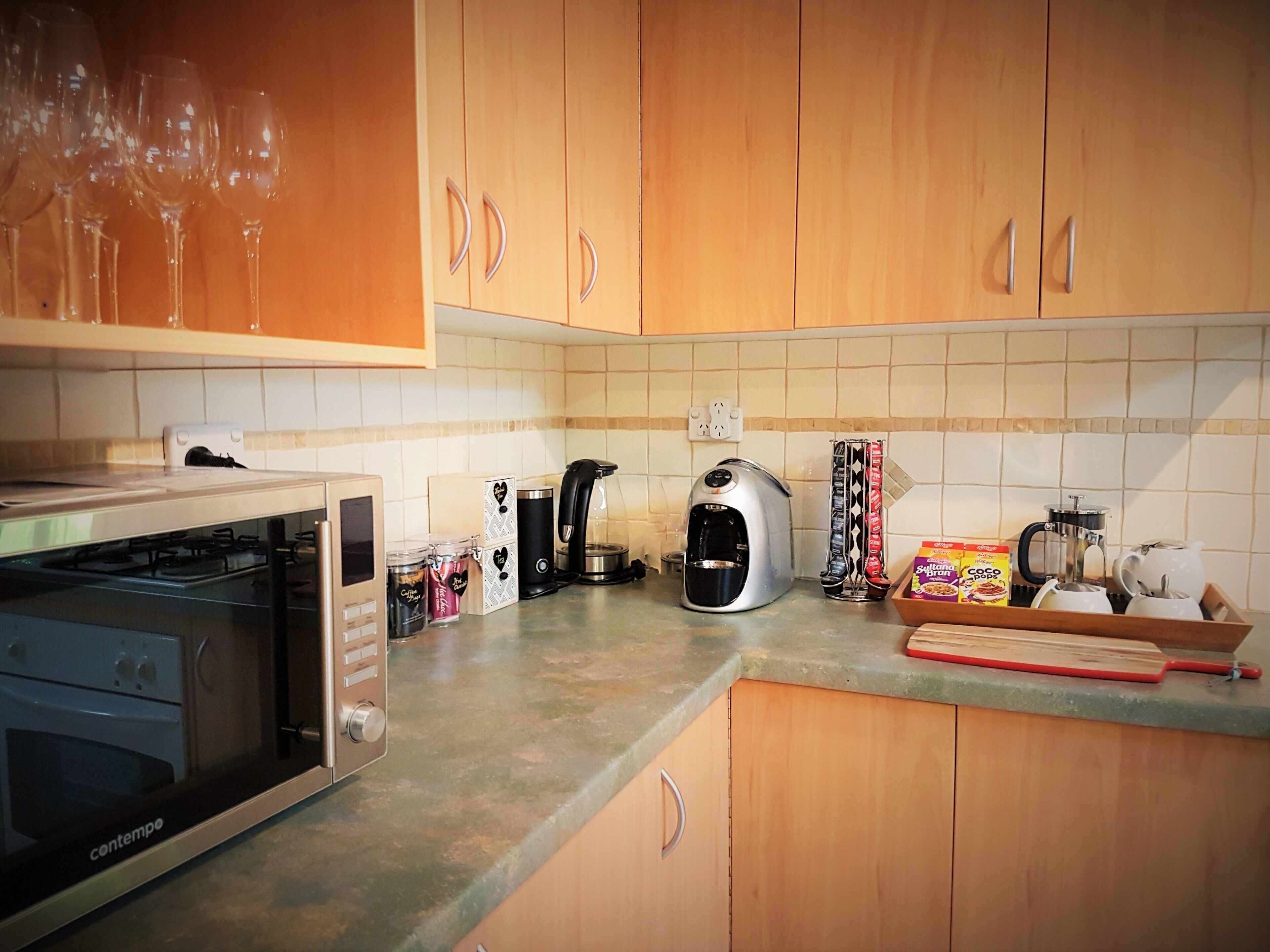 Cozinha com fogão a gás, cafeteira, torradeira e diversos utensílios de cozinha na bancada.