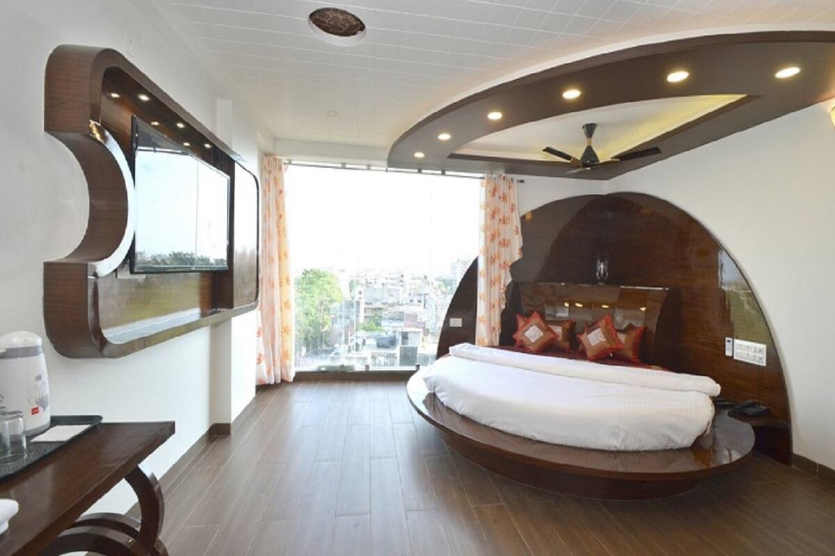 A modern bedroom with a curved bed, a large window, and a view of the city.