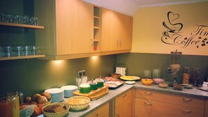 Disposición de bufé con diversos alimentos y bebidas, armarios de madera y un letrero en la pared que dice "Tim Coffee".