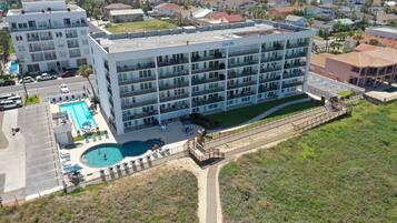 A multi-story hotel with a swimming pool, outdoor seating, and a view of the surrounding neighborhood.