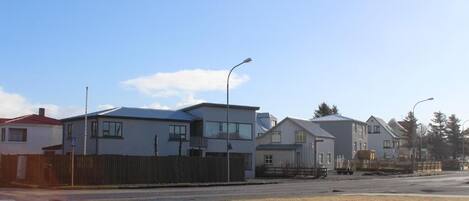 A residential street with modern houses, a clear sky, and a streetlight.