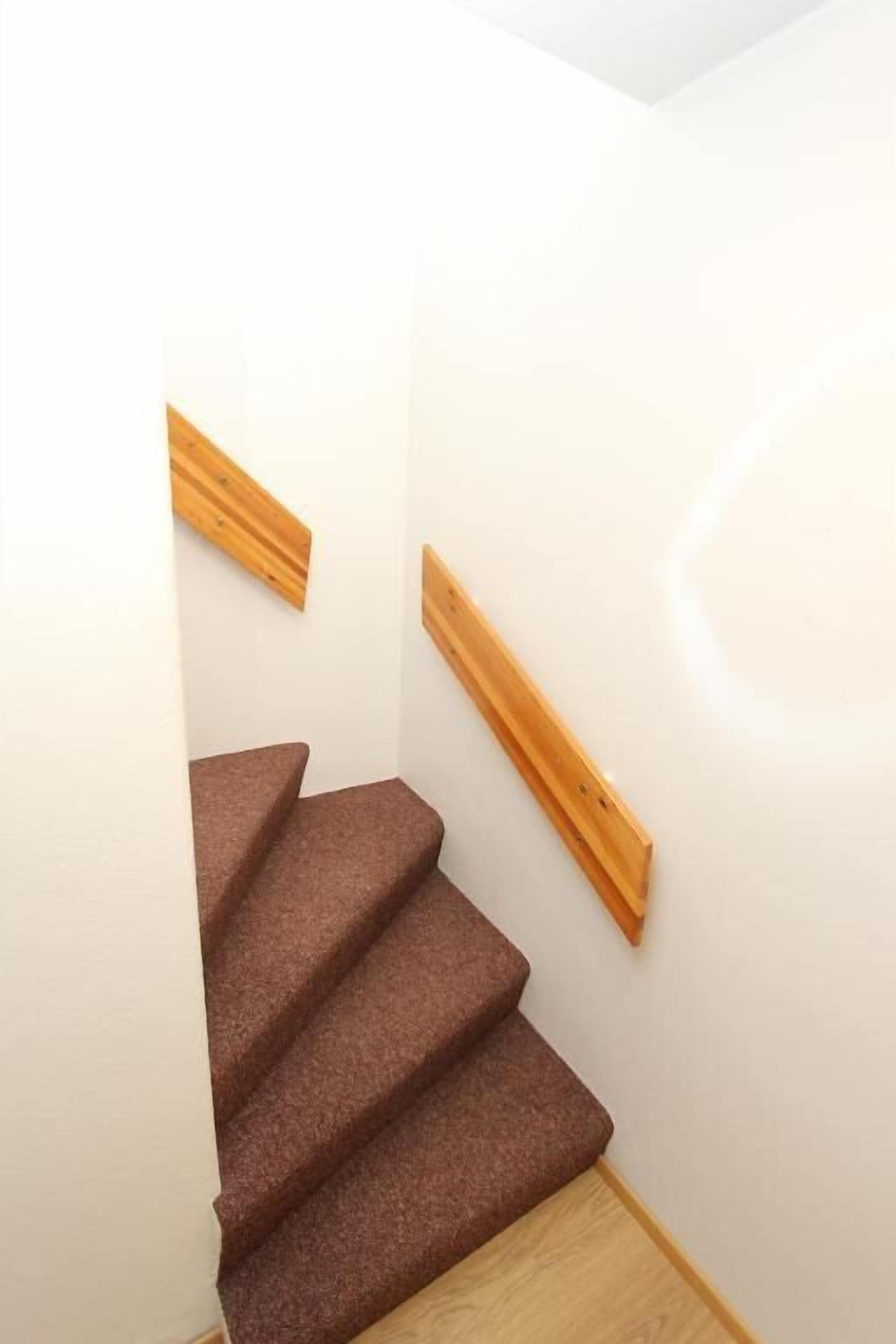 Un escalier avec des rampes en bois et des marches recouvertes de moquette.