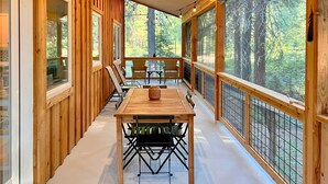 Eine Holzterrasse mit Tisch und Stühlen mit Blick auf einen Wald.