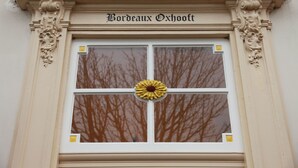 A window with a decorative wreath and the name "Bordeaux Oxhooft" above it.