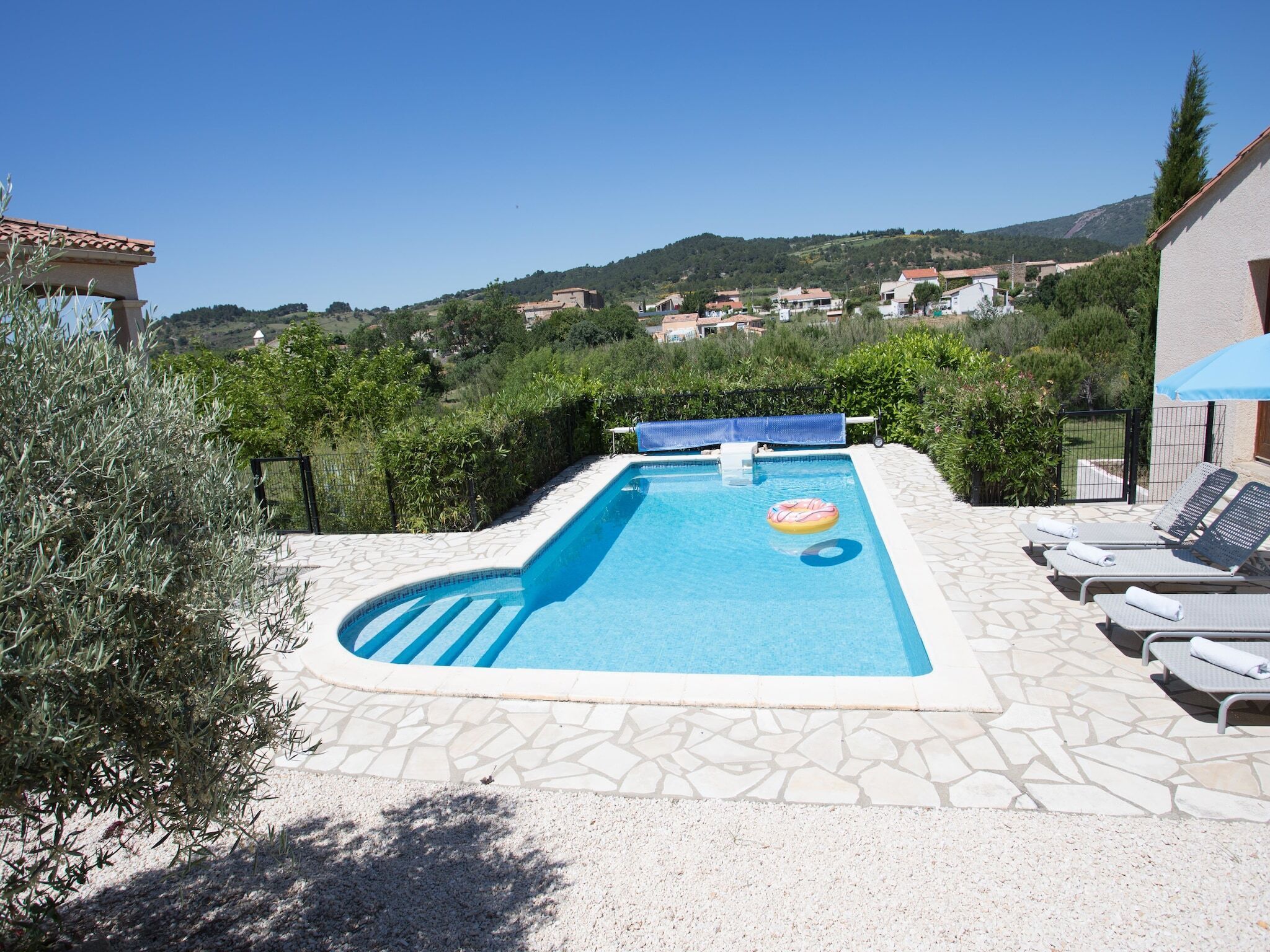 A swimming pool with a view of a hillside, lounge chairs, and a pergola.