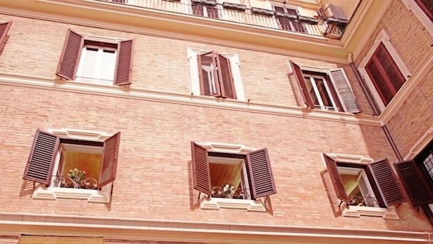 Um edifício de vários andares com fachada de tijolos, várias janelas com persianas e sacadas.