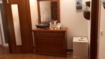 Un comò in legno con uno specchio, un modellino di nave, candele e una cornice con una foto.