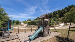 Ein Spielplatz mit Rutsche, Klettergerüsten und einer Schaukel.