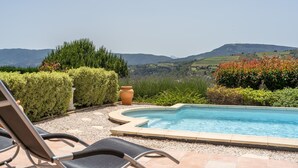 A pool area with a view of the countryside, including hills and a statue.