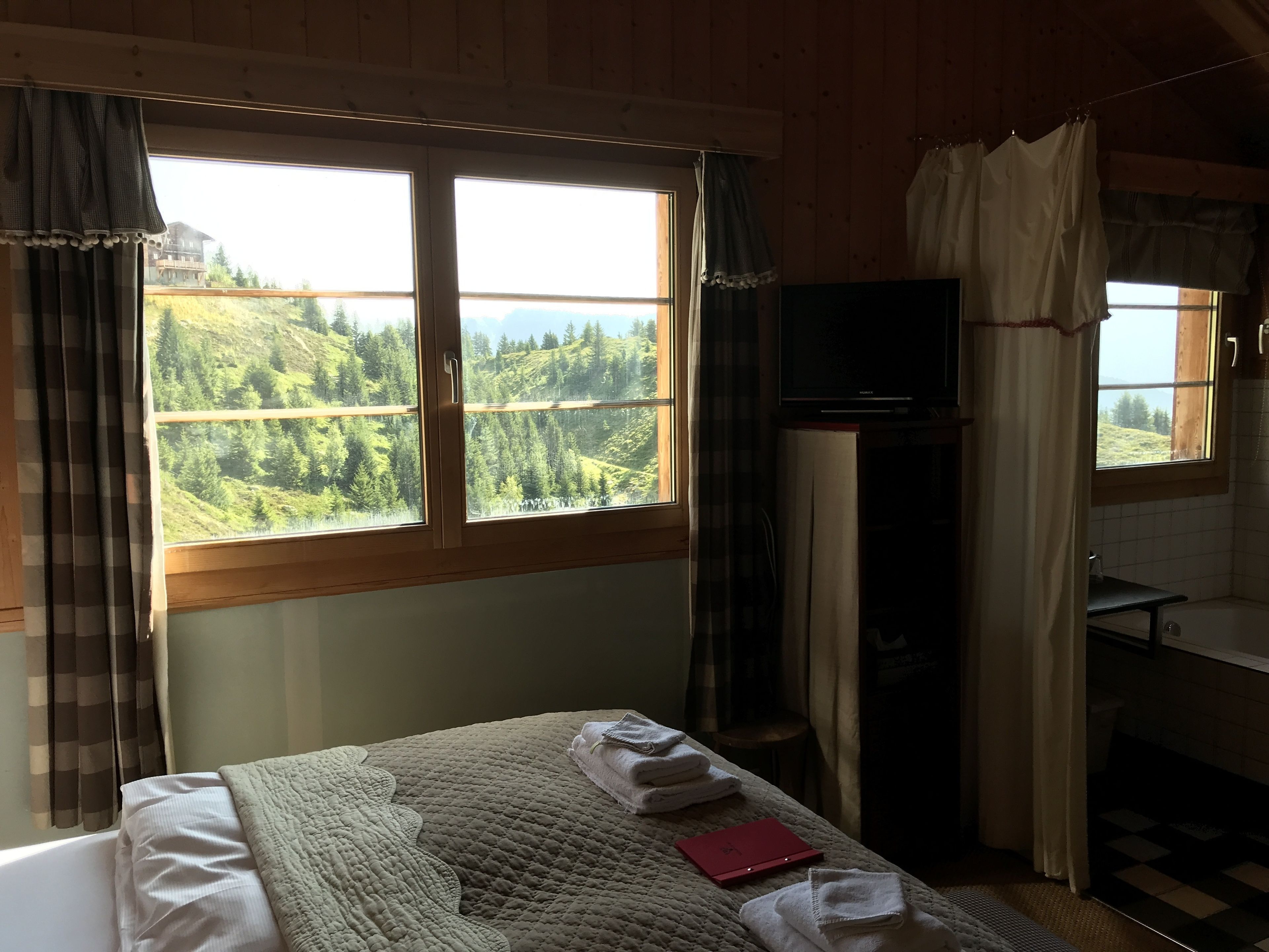 A bedroom with a bed, a TV, and a bathroom.
