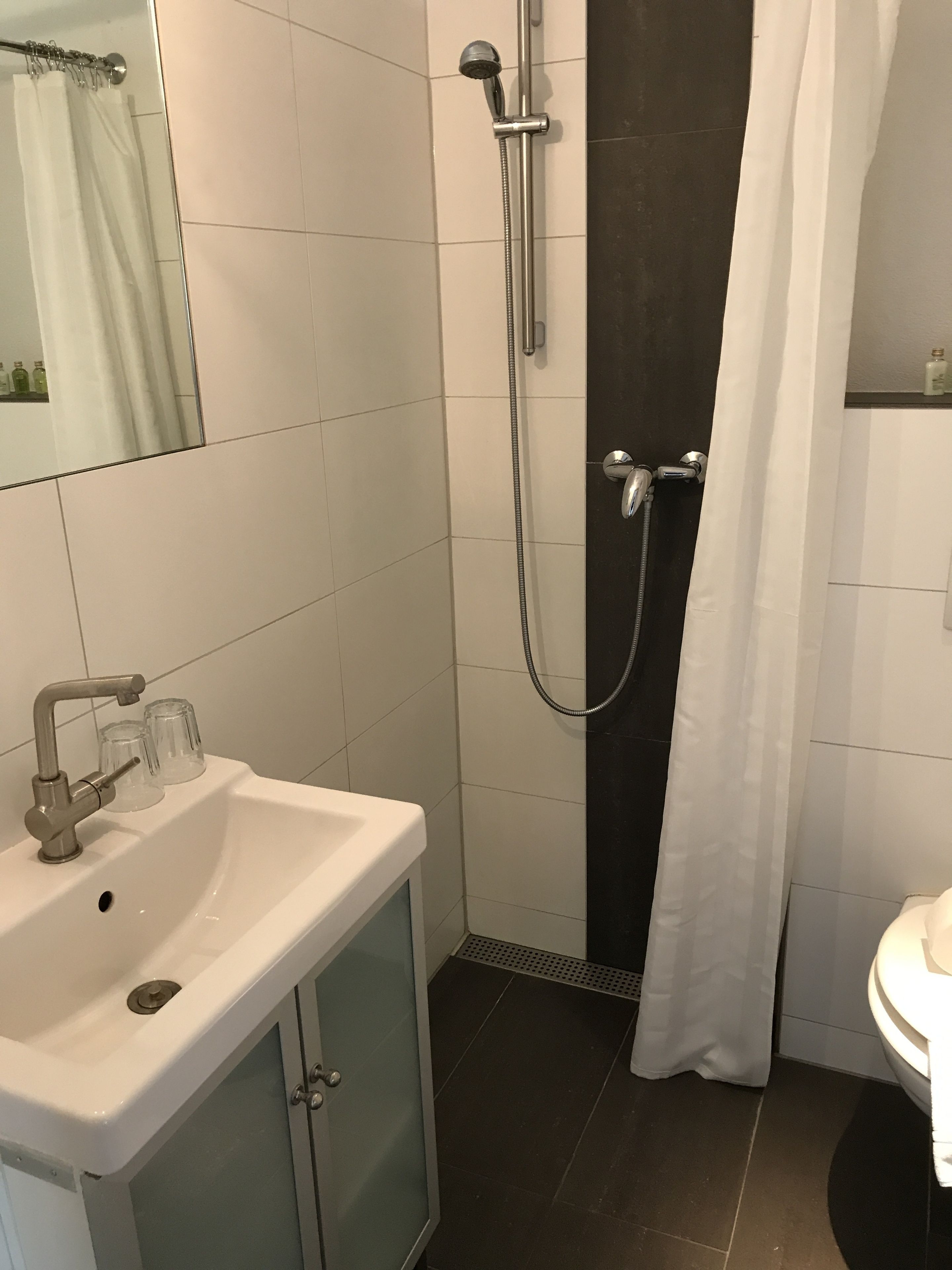 A bathroom with a white sink, a shower with a glass door, and a mirror above the sink.