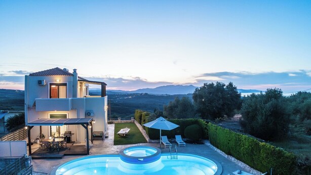 Une maison moderne à deux étages, dotée d’une piscine, d’un espace salon extérieur et offrant une vue sur la campagne.