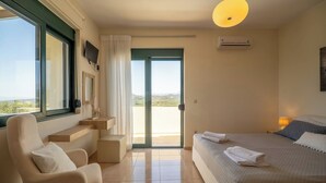 Une chambre à coucher comprenant un lit, une chaise, un bureau, un téléviseur et une vue sur l’extérieur.