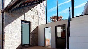 A modern interior with a stone wall, wooden flooring, and a view of the sky through a large window.