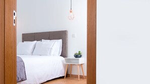 A bedroom with a bed, bedside table, and a hanging light fixture.