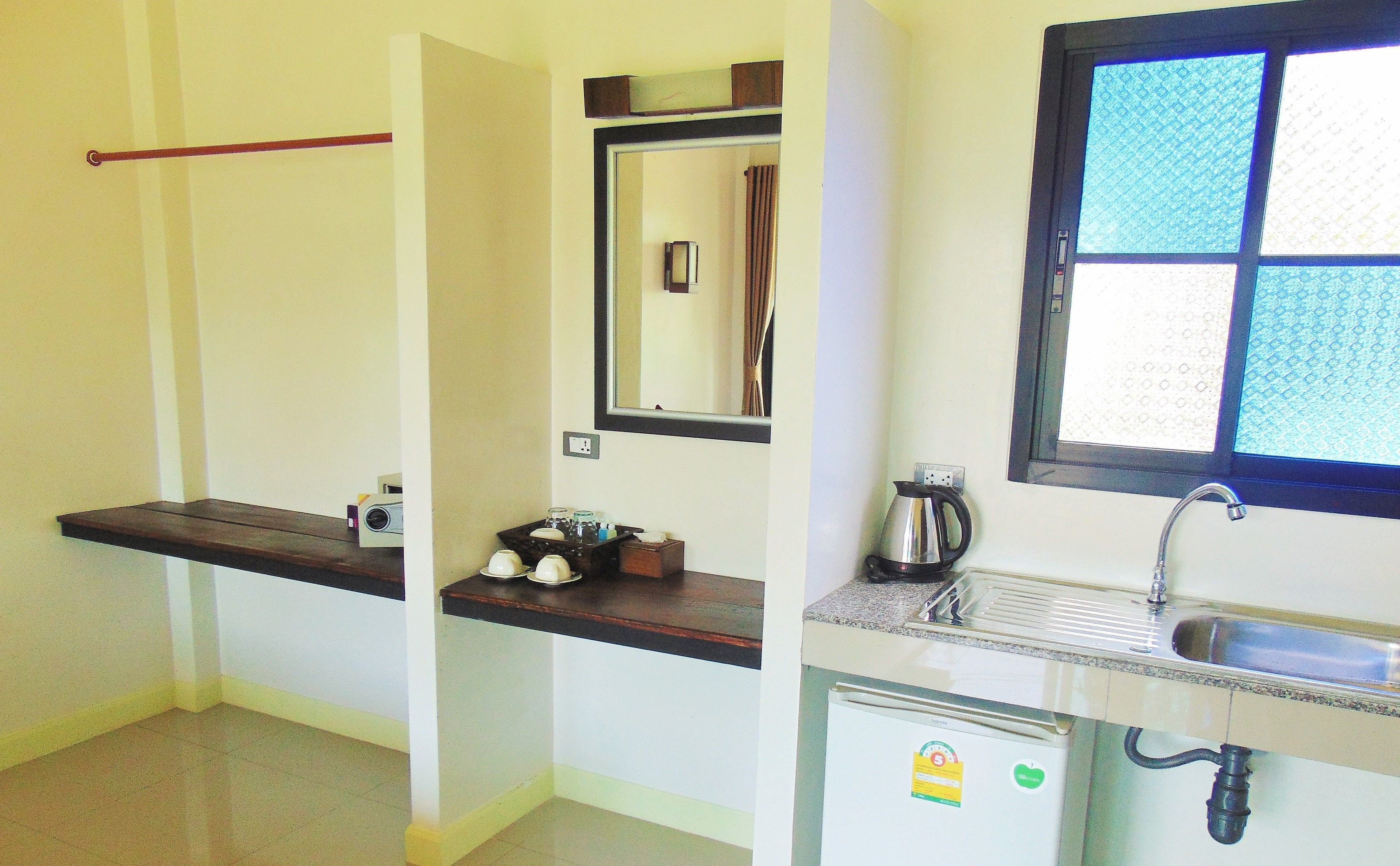 A compact kitchen with a small refrigerator, a sink, and a window with a view.