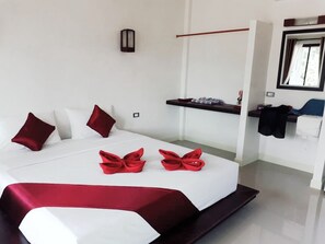 Ein Hotelzimmer mit einem aufgeräumten Bett, einem Nachttisch, einem Spiegel und einem Regal mit Handtüchern.