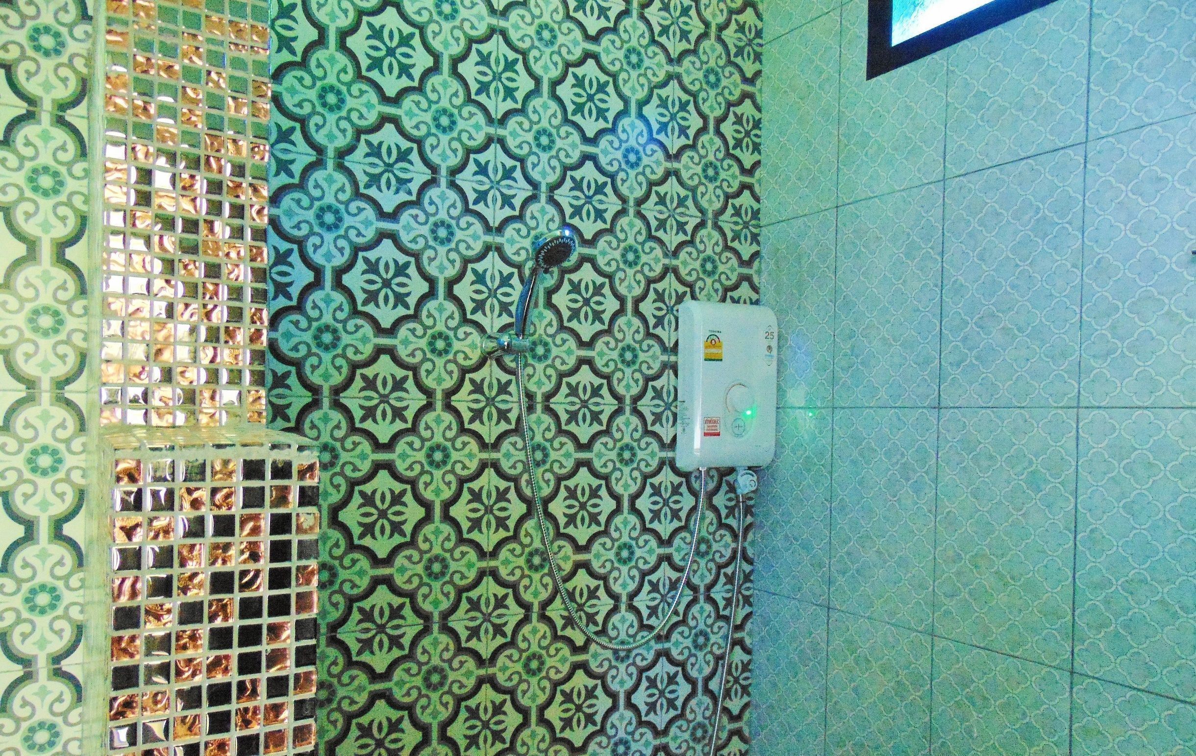 A bathroom with patterned tiles, a shower, and a water heater.