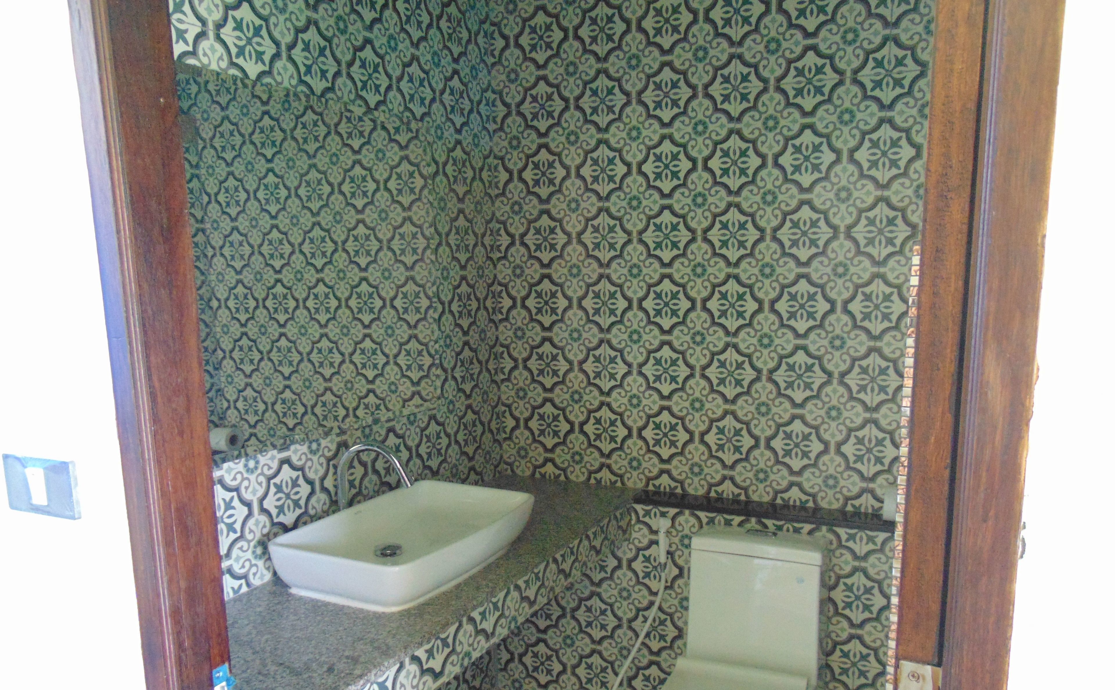 A bathroom with a sink, a toilet, and patterned tiles on the walls.