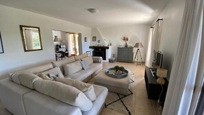 A modern living room with a sofa, a coffee table, and a TV stand. There is a fireplace and a dining area visible in the background. - Relaxing Retreat Near Minerve (Cesseras)