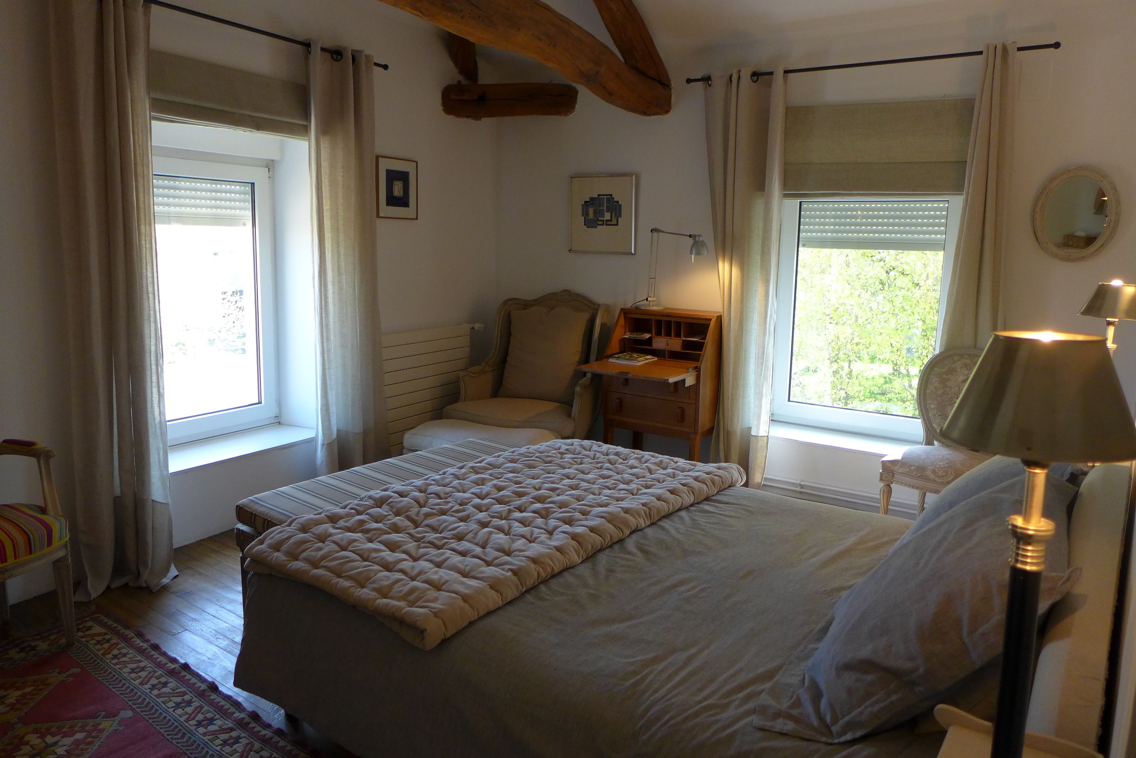 A bedroom with a bed, a chair, a desk, and a lamp.