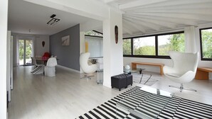 A spacious living area with a large window, a modern chair, a bench, and a striped rug. - Villa in Malves near Carcassonne Pool (Malves en Minervois)