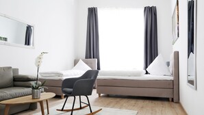 Een moderne woonkamer met een bank, een schommelstoel, een salontafel en een bed met gordijnen.