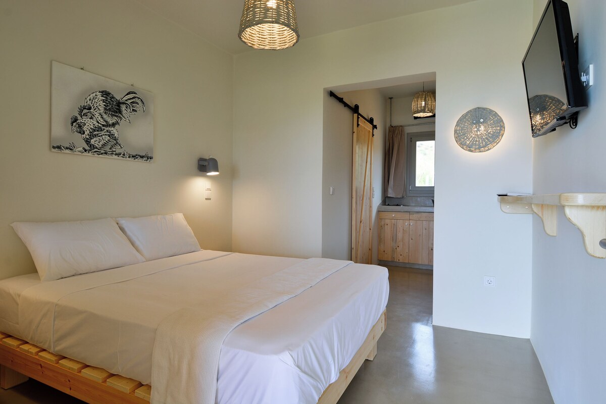 A bedroom with a wooden bed, a wall-mounted TV, and a ceiling light fixture.