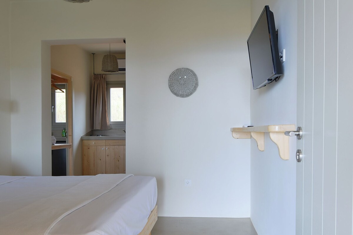 A bedroom with a wooden bed, a television mounted on the wall, and a small shelf.