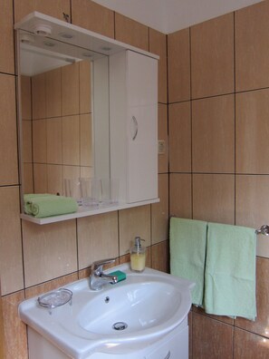 A bathroom with a white sink, a mirror above it, and a green towel hanging on a rack. - Nada Apartments (Opatija)
