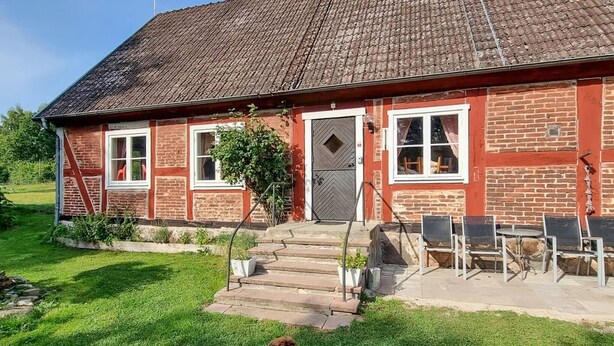 A red brick house with a tiled roof, a front door, and a small front yard with a dog. - Gorgeous home in Vinslöv with WiFi (Vinslöv)