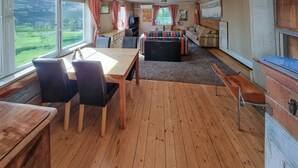 A cozy cabin interior with a wooden floor, a dining table with chairs, a sofa, and a small kitchen area. - Gorgeous home in Vinslöv with WiFi (Vinslöv)