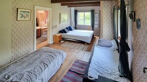 A bedroom with two single beds, a wooden floor, patterned wallpaper, a small wooden stool, and a window with curtains. - Gorgeous home in Vinslöv with WiFi (Vinslöv)