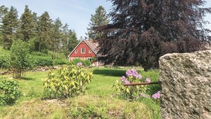A red barn in a rural setting with a stone wall, green grass, and purple flowers. - Gorgeous home in Vinslöv with WiFi (Vinslöv)