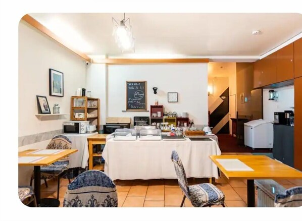 A dining area with a buffet setup, a refrigerator, and a chalkboard menu on the wall.