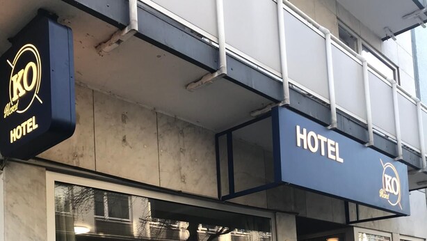 Entrada de hotel con un amplio ventanal que muestra diversos artículos.