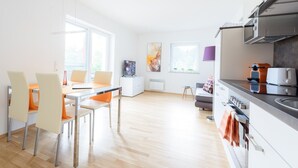 A modern kitchen with a dining area, large windows, and a view of the outdoors. - Modern apartment with large balcony on Lake Klopein (St. Kanzian)